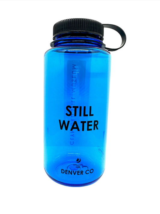 Slate blue with black cap Nalgene's classic 32oz wide-mouth water bottle with slogan “STILL WATER”.
