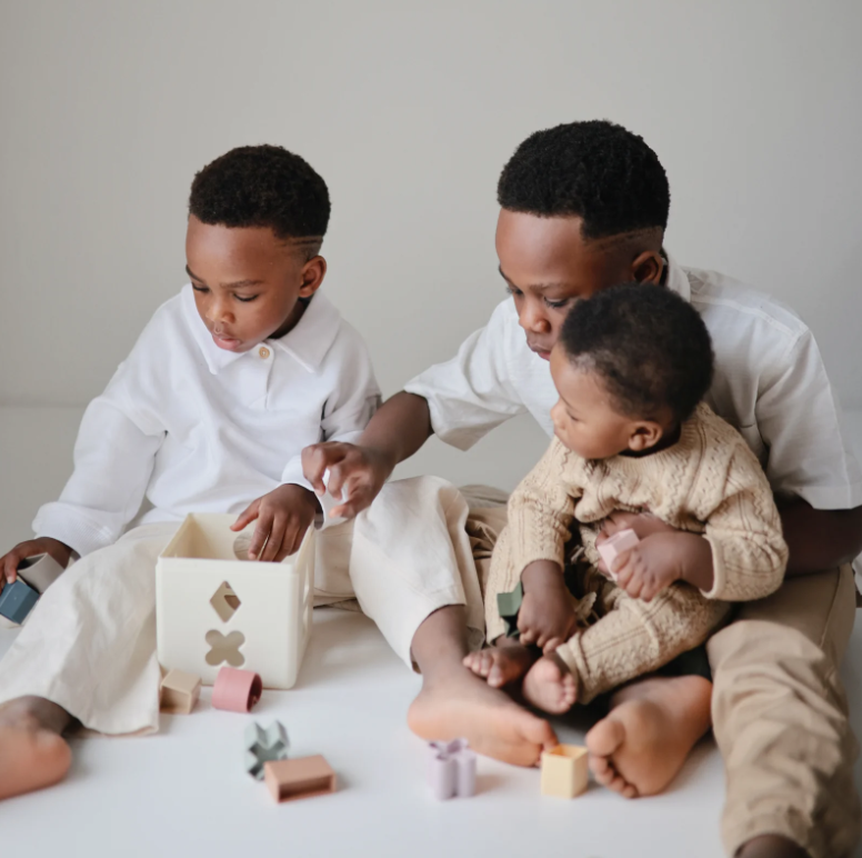 Three children playing with the Shape Sorting Box.