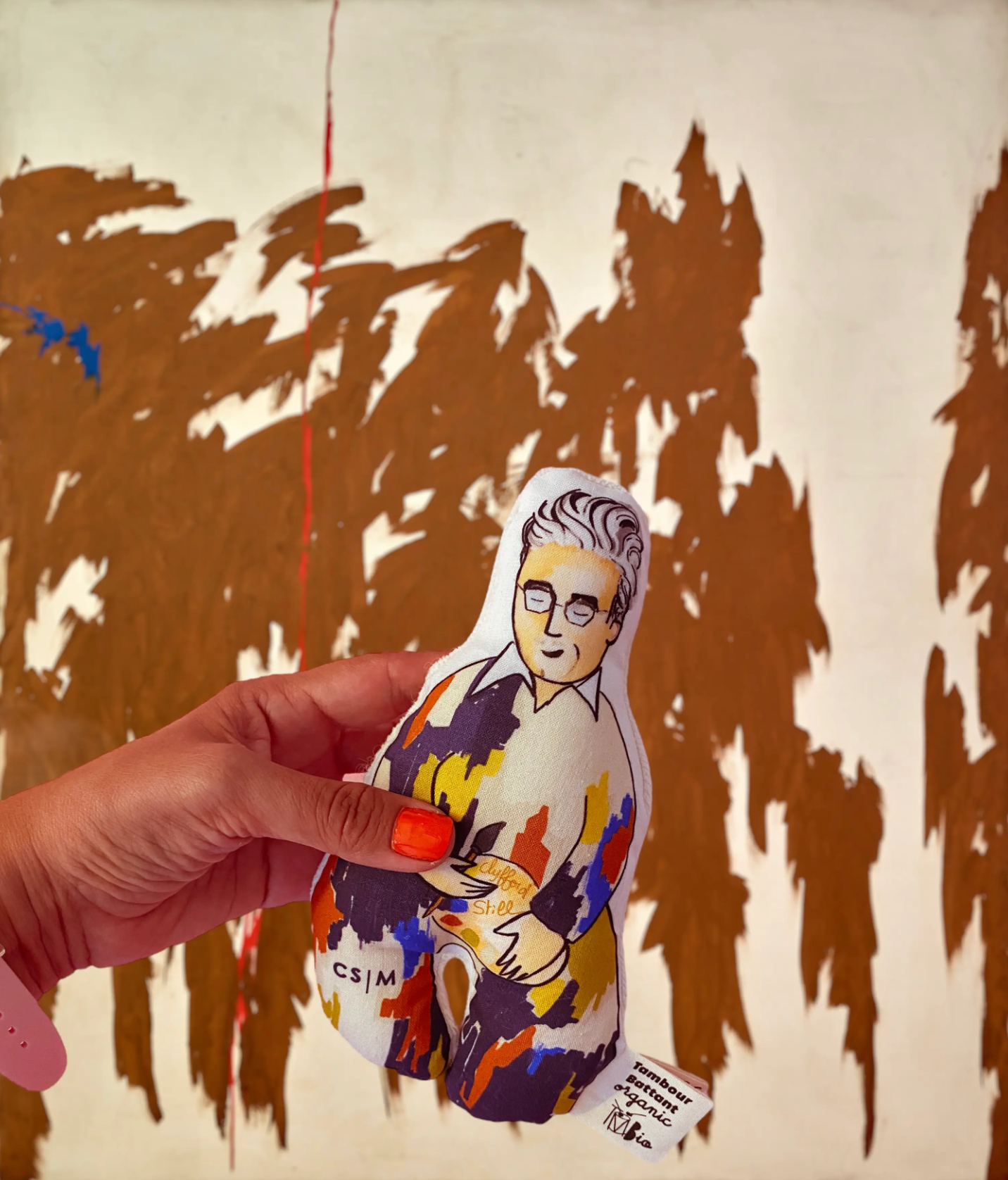 Hand holding Clyfford Still rattle in front of one of his paintings.