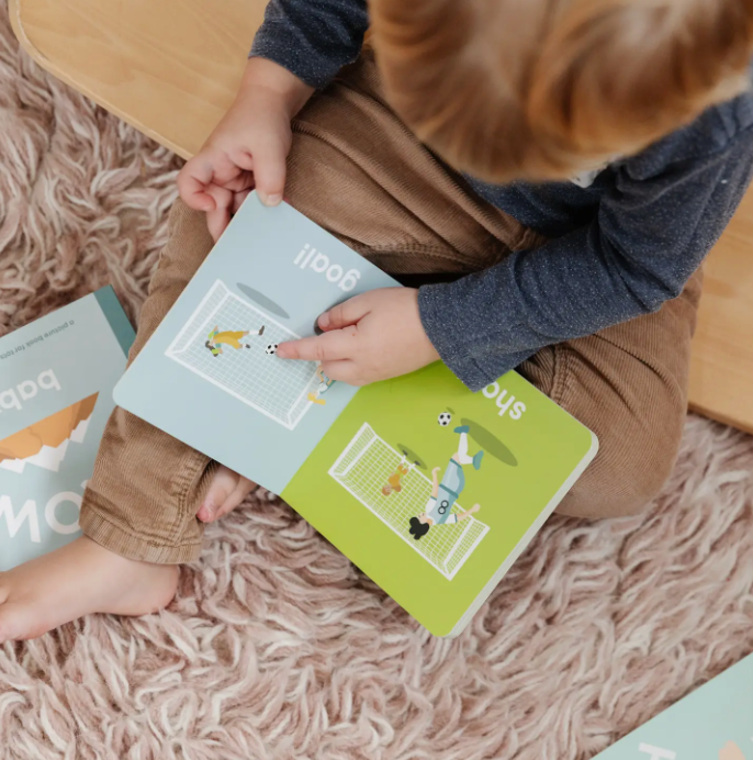 Top view of a toddler pointing at a square picture book