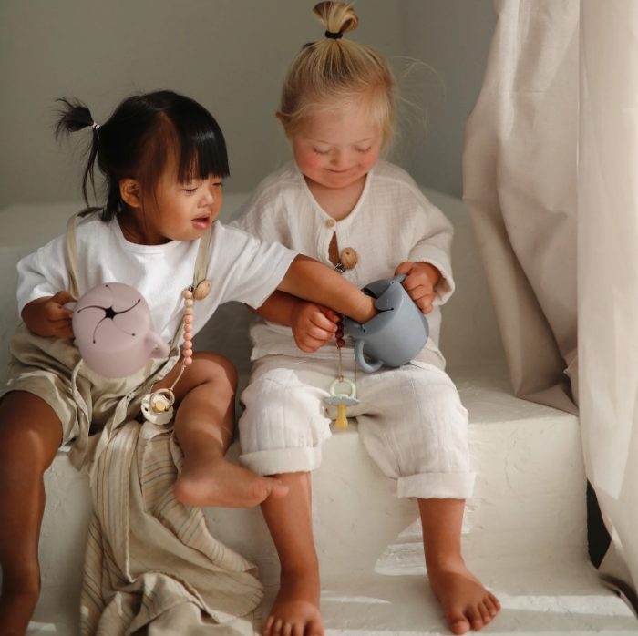Photo of two toddlers holding Snack Cups one reaching into the others.