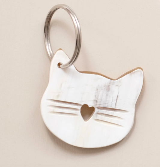 Cat-shaped keychain with a heart detail on a beige background