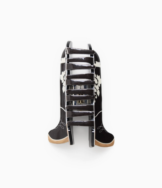 A pair of black cowboy boots with white floral embroidery and light brown soles, displayed on a white background.