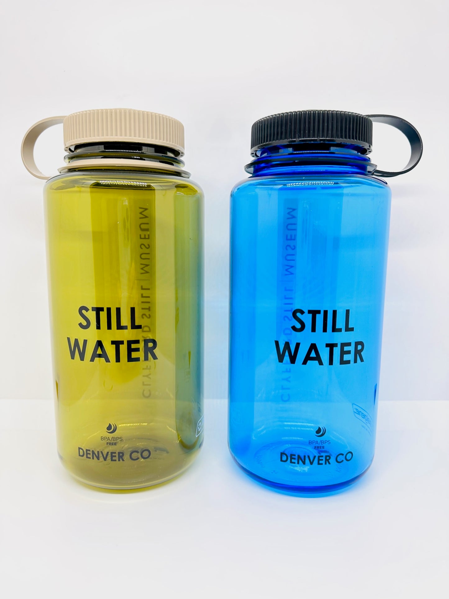 Two Nalgene's classic 32oz wide-mouth water bottle with slogan “STILL WATER”. Olive with mocha cap on left, slate blue with black cap on right.