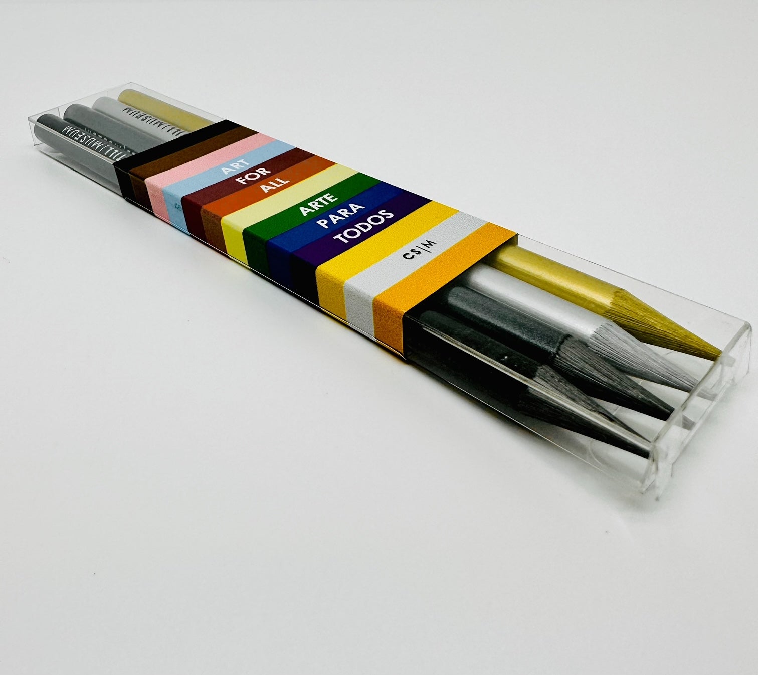 Set of four solid-woodless graphite pencils in Silver, Black, Gold, and pure color.  They come in a clear transparent package, wrapped with a rainbow belly band with the slogan “ART FOR ALL; ARTE PARA TODOS”  around the box.