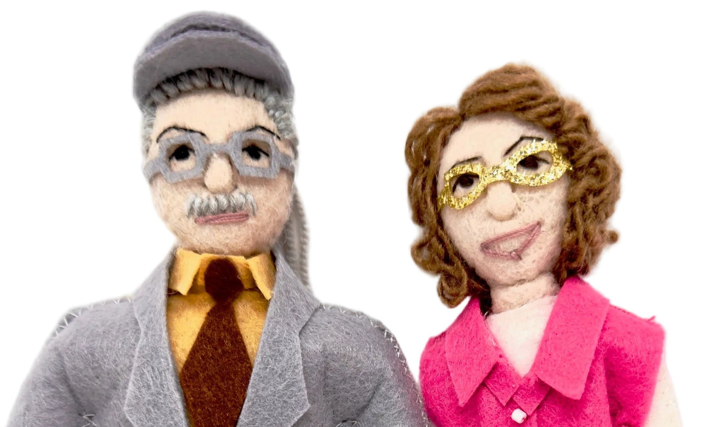 Two felt ornaments,  one in a gray coat and the other in a pink outfit, standing next to each other on a white background.