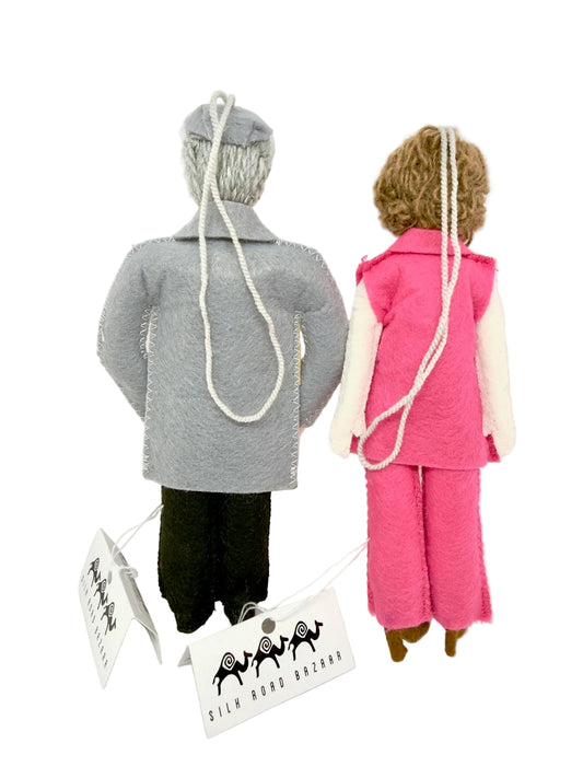 Two felt ornaments wearing outfits with a brand label in the foreground.