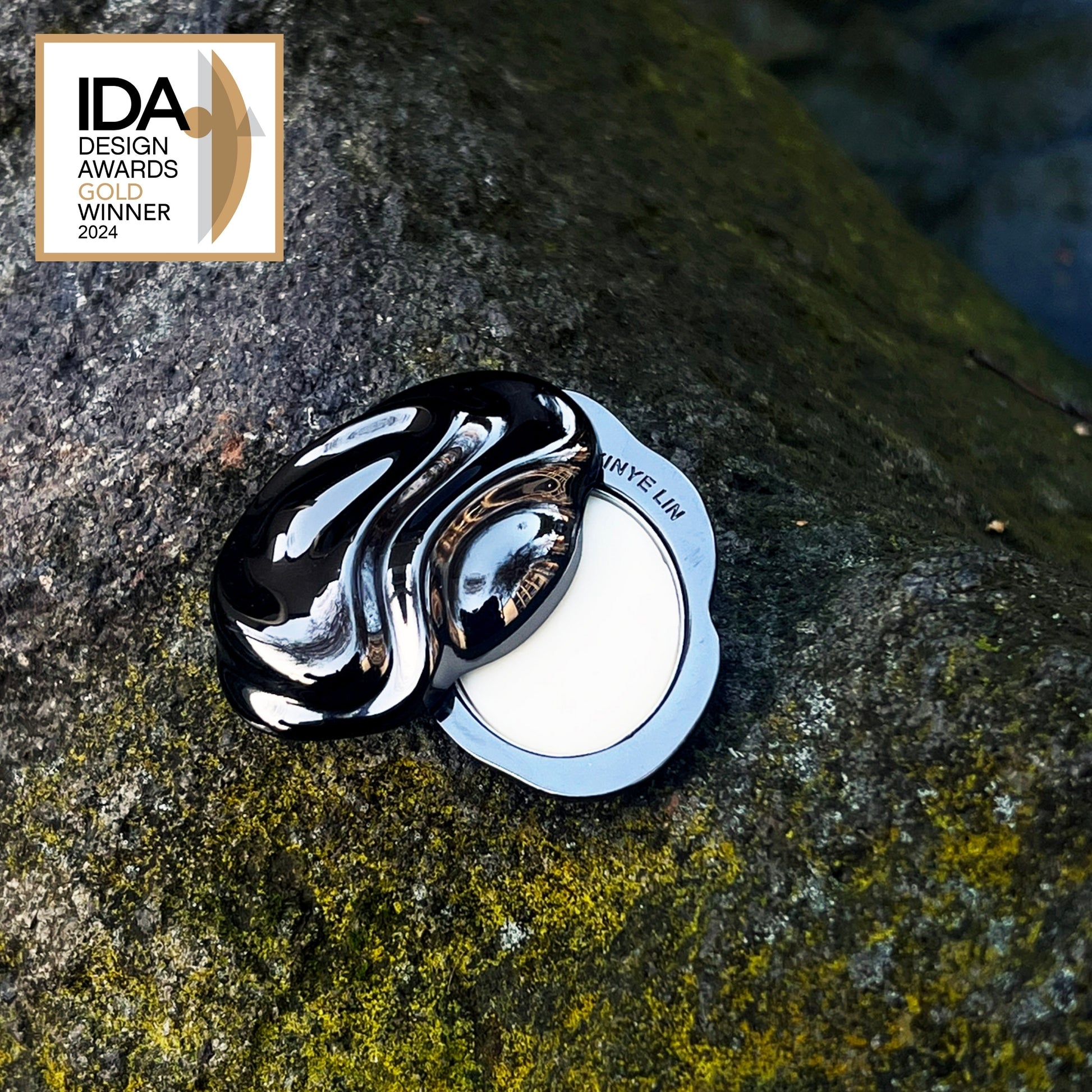 Black and white decorative object on a textured stone surface with IDA Design Awards 2024 Winner badge.