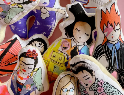 Pile of soft fabric rattles with artist illustrations.