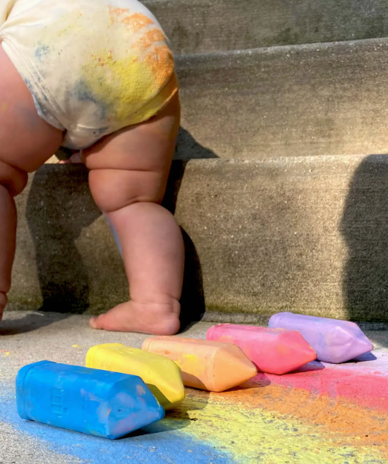 Image of young child with rainbow color chalk dust on body.