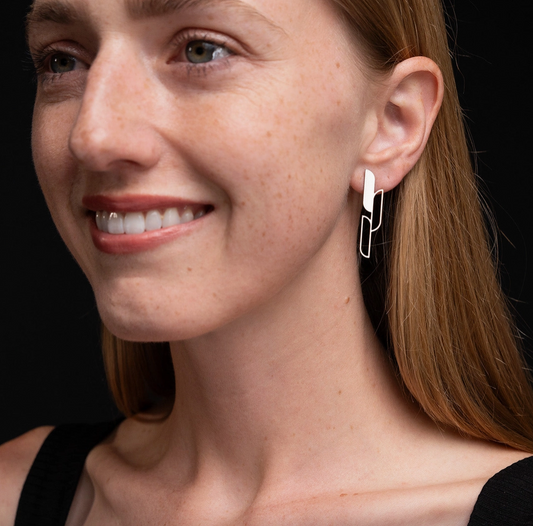 Close-up of a woman wearing Ascend earrings with a black background.