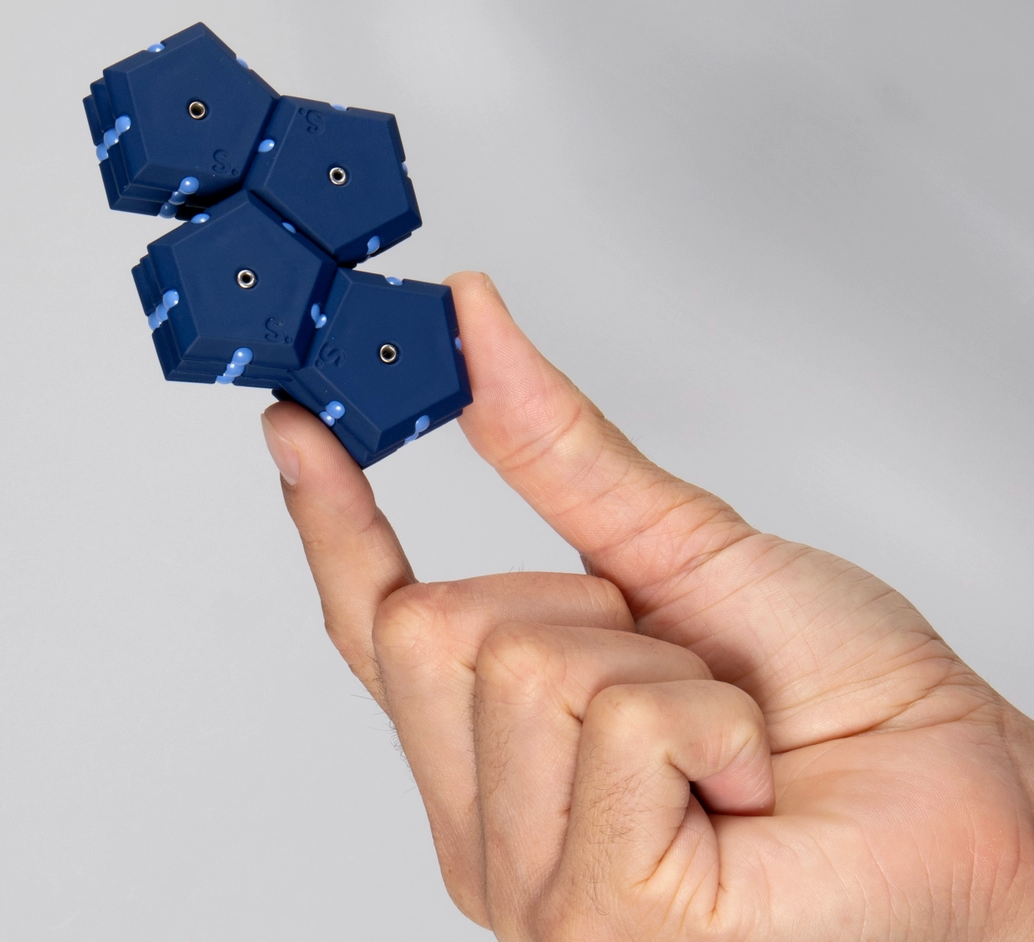 Blue fidget pieces held between fingers against a gray background