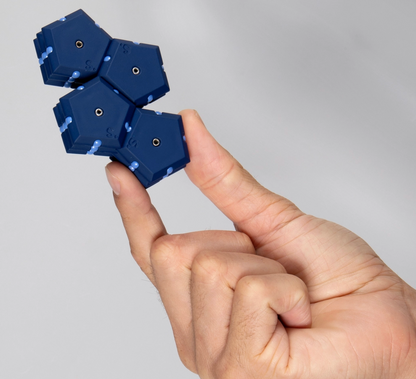 Blue fidget pieces held between fingers against a gray background