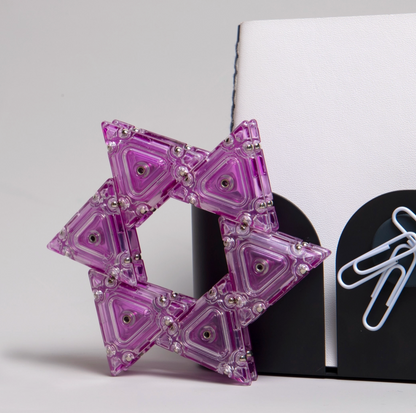 Purple geometric star-shaped object with magnets on a white background