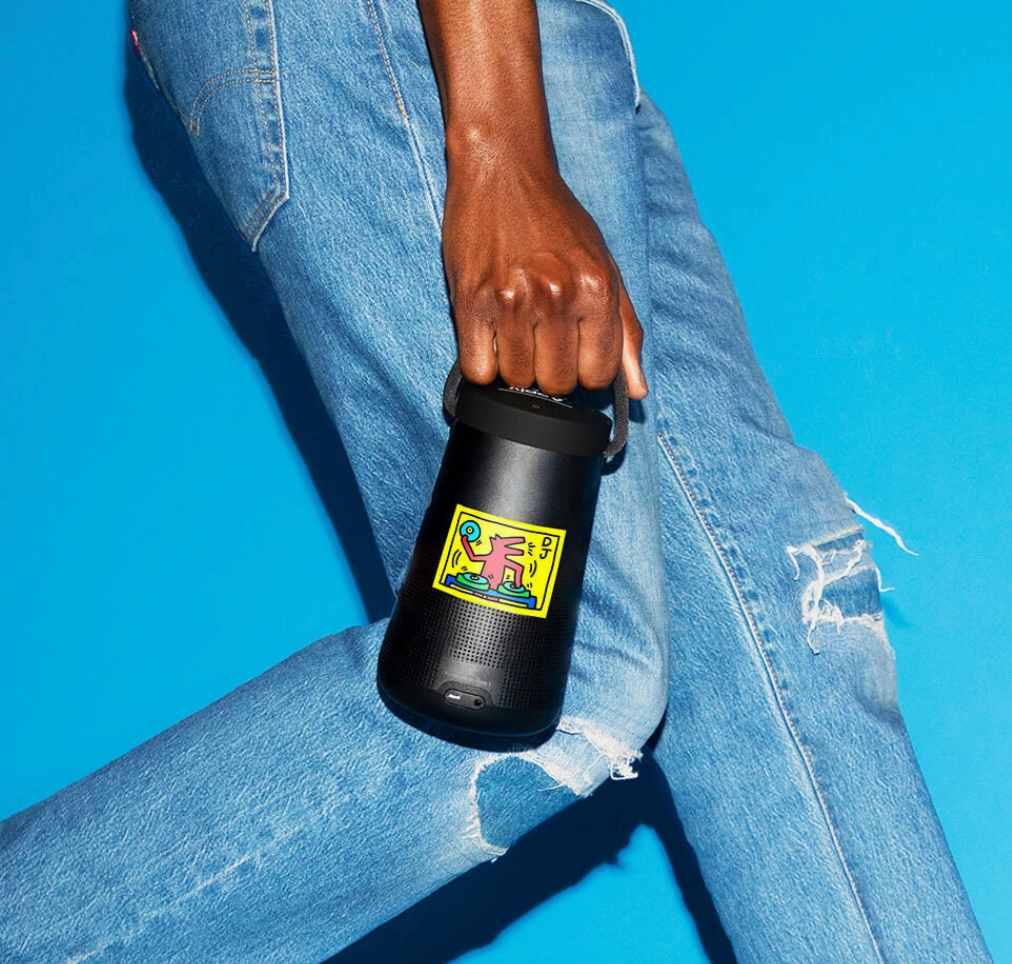 Person holding a black water bottle with a colorful label against a blue background