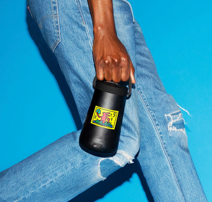 Person holding a black water bottle with a colorful label against a blue background