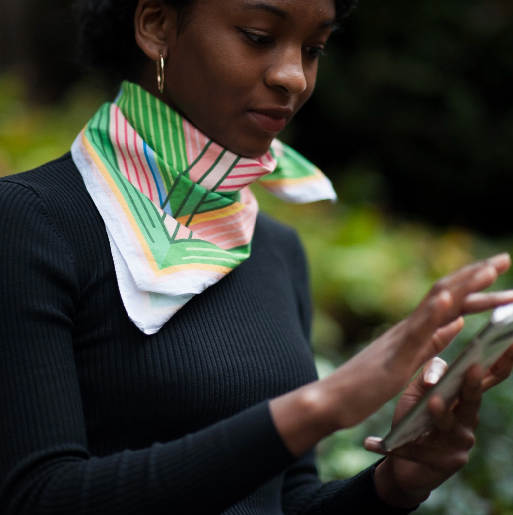Woman wearing a colorful scarf and using a smartphone outdoors