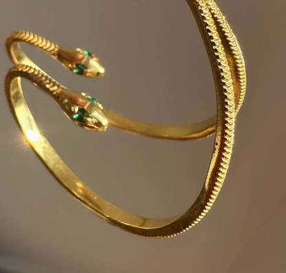 Gold snake-shaped hoop earrings on a plain background.