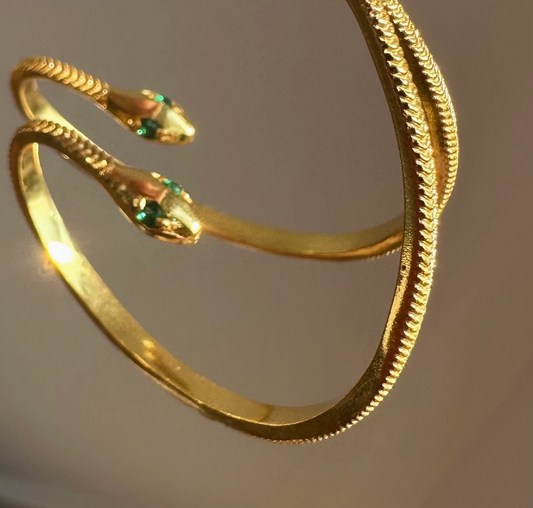 Gold snake-shaped hoop earrings on a plain background.