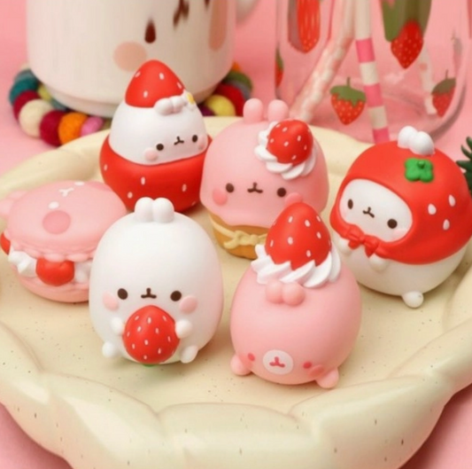 Set of cute strawberry-themed figurines on a pink background