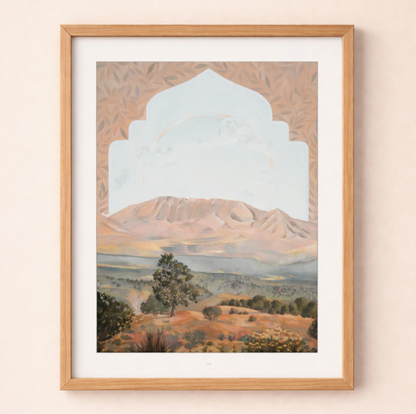 Framed artwork of a mountain landscape with an archway on a beige wall