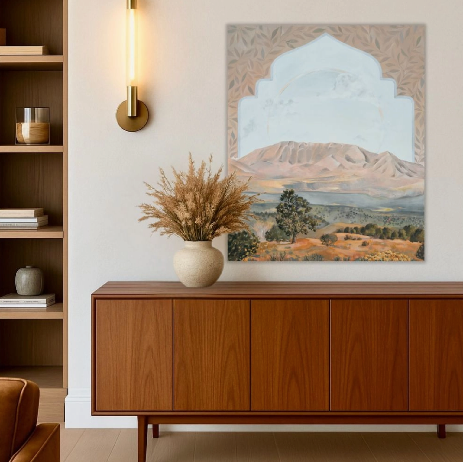 Wooden sideboard with decorative vase and plant in a room with wall art of a mountain landscape.