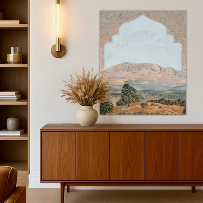 Wooden sideboard with decorative vase and plant in a room with wall art of a mountain landscape.