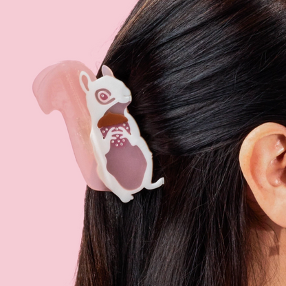 Hair clip with cartoon character attached to a person's hair against a pink background