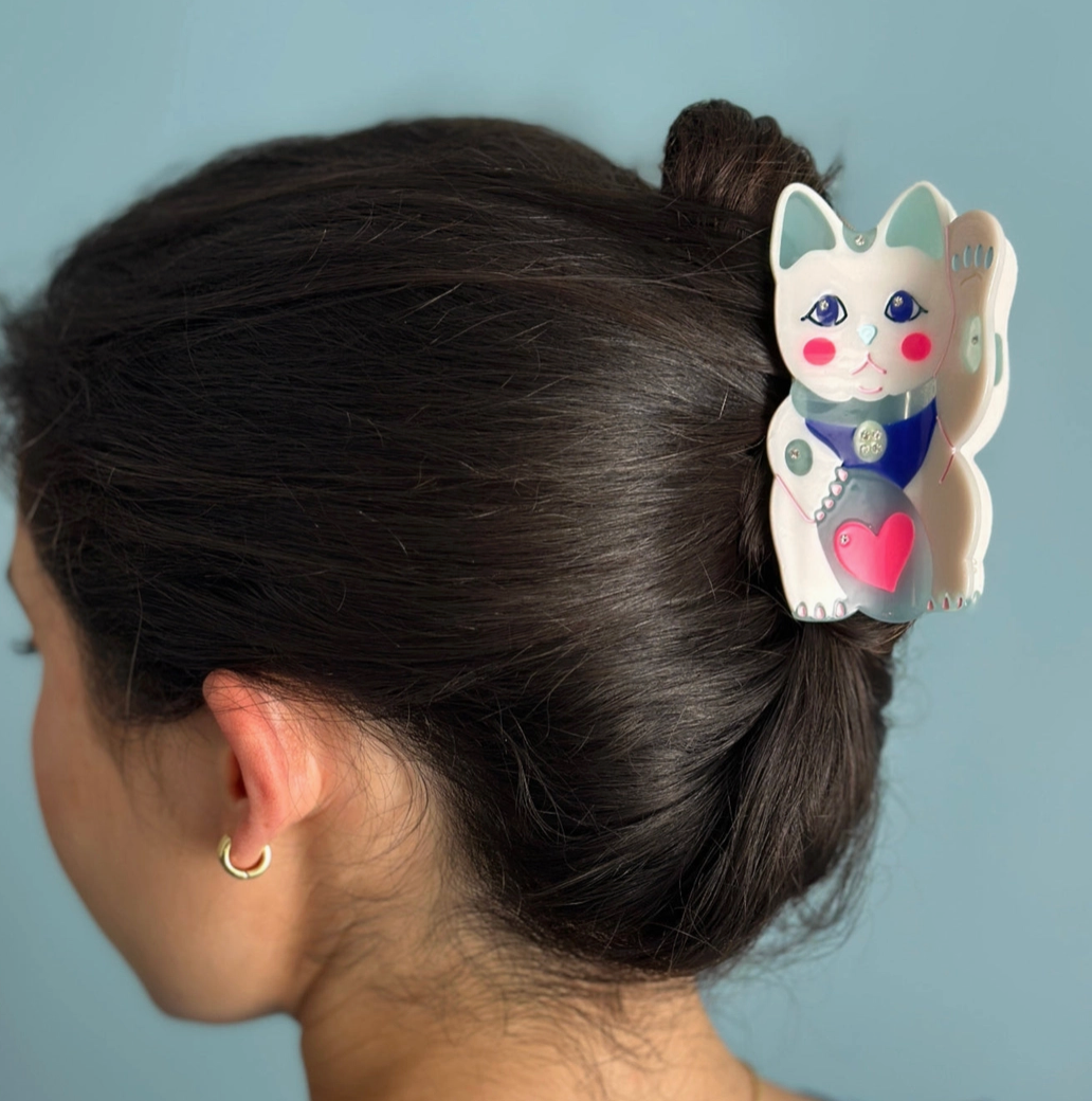 Person with a hair clip shaped like a lucky cat with a heart on a blue background