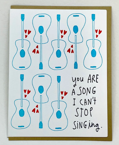 Greeting card with acoustic guitar illustrations and text 'You are a song I can't stop singing' on a white background.