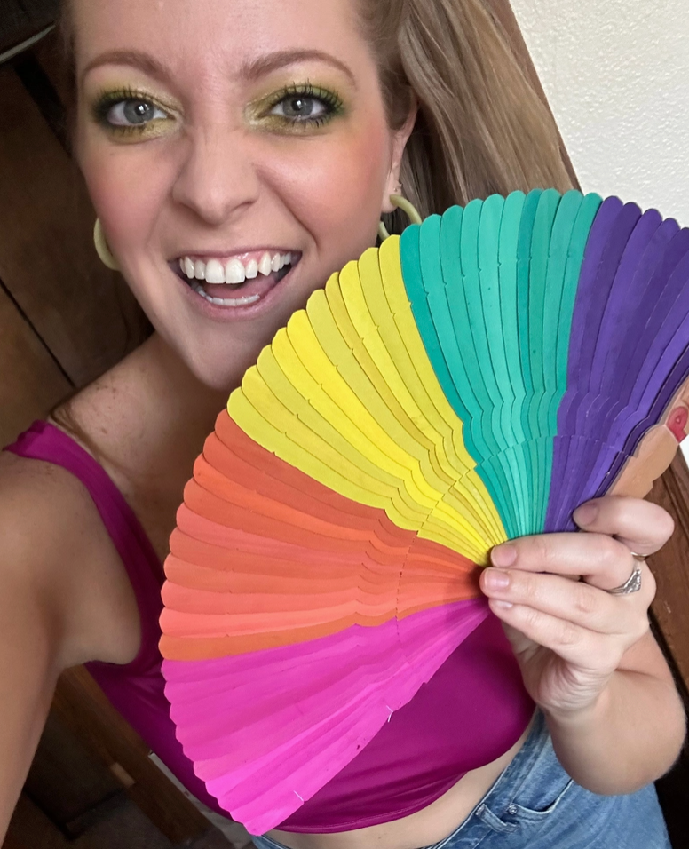 Woman holding a colorful fan with a rainbow pattern