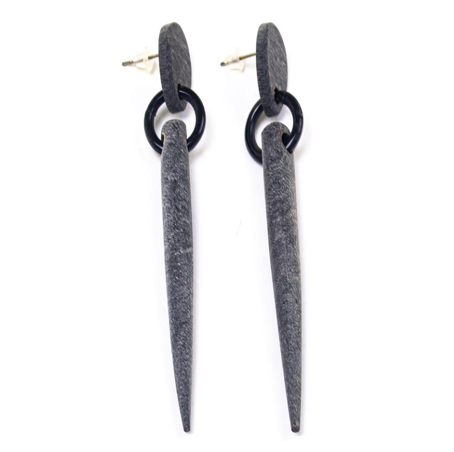 Pair of earrings with black circular top and long gray spike on a white background