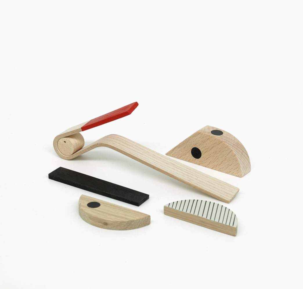 A set of wooden toy or educational blocks and a curved wooden piece with a red handle, arranged on a plain white background.