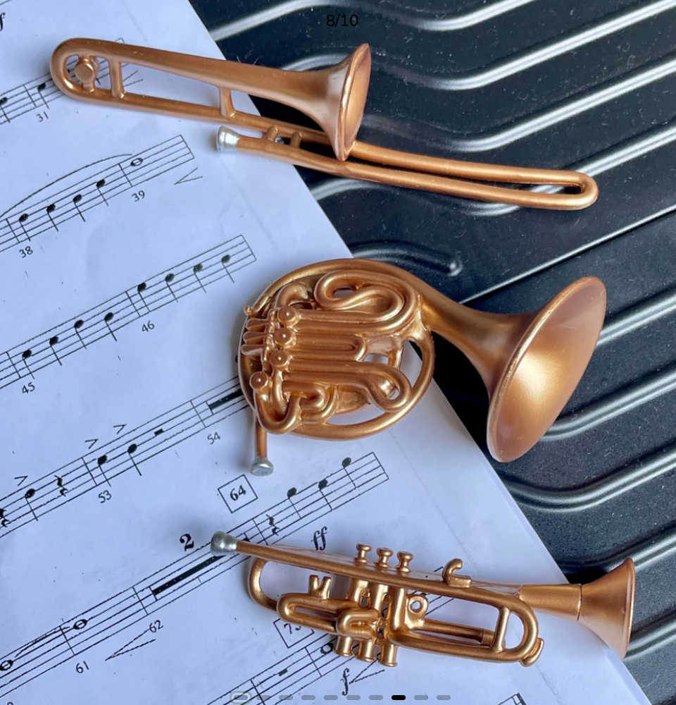 Gold brass instruments including a trombone, horn, and trumpet on sheet music.