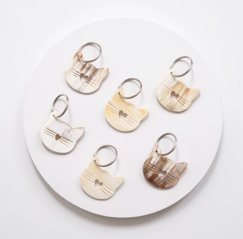 Set of six cat-shaped keychains on a round white plate