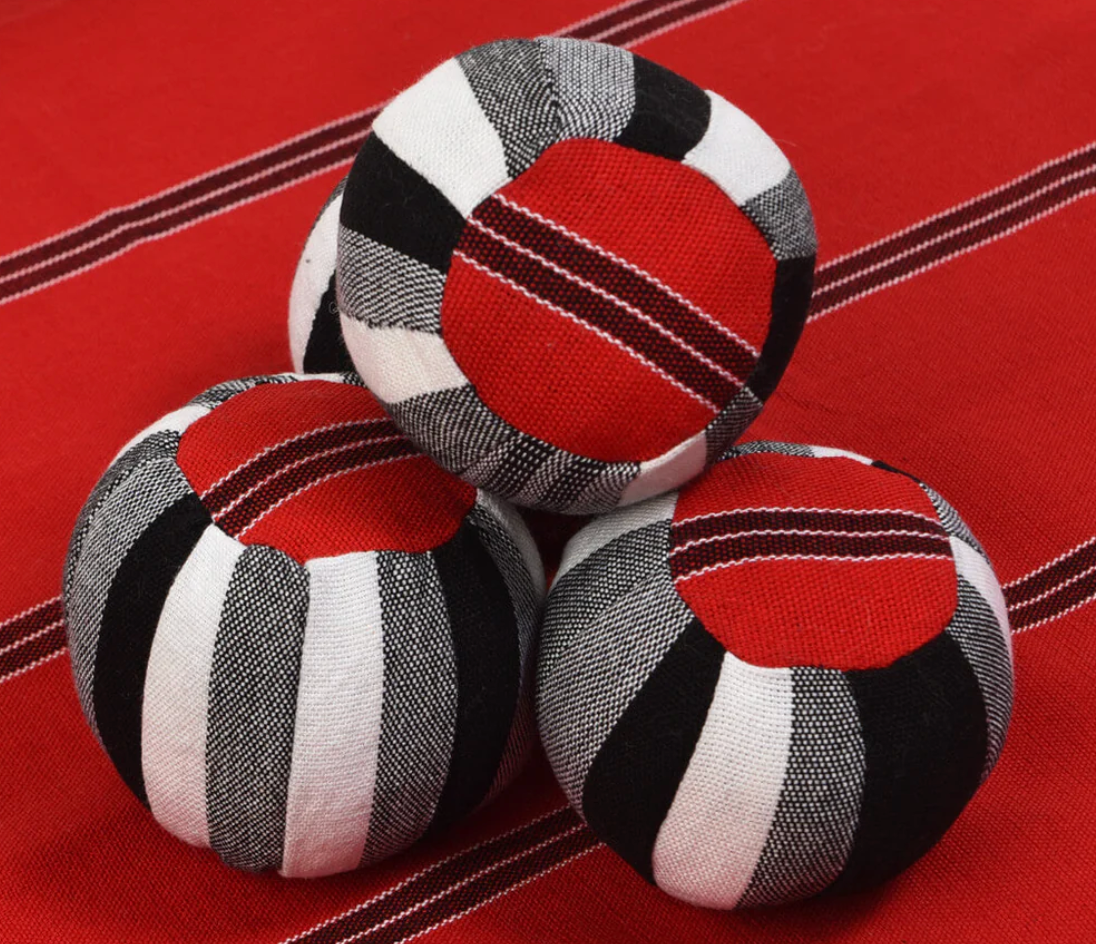 Three striped fabric balls on a red surface with a striped pattern.
