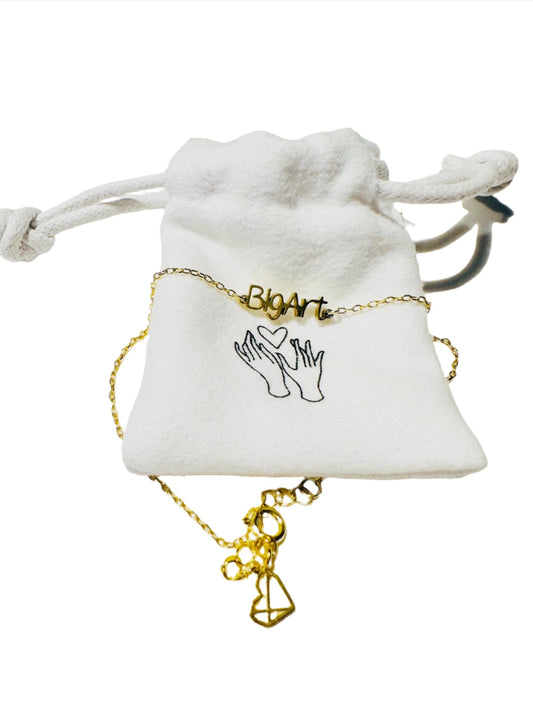 Delicate chain with a with a word charm reading ’BigArt’ with fabric bag packaging