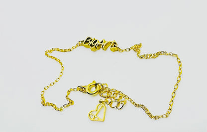 Delicate gold chain with a with a word charm reading ’BigArt’