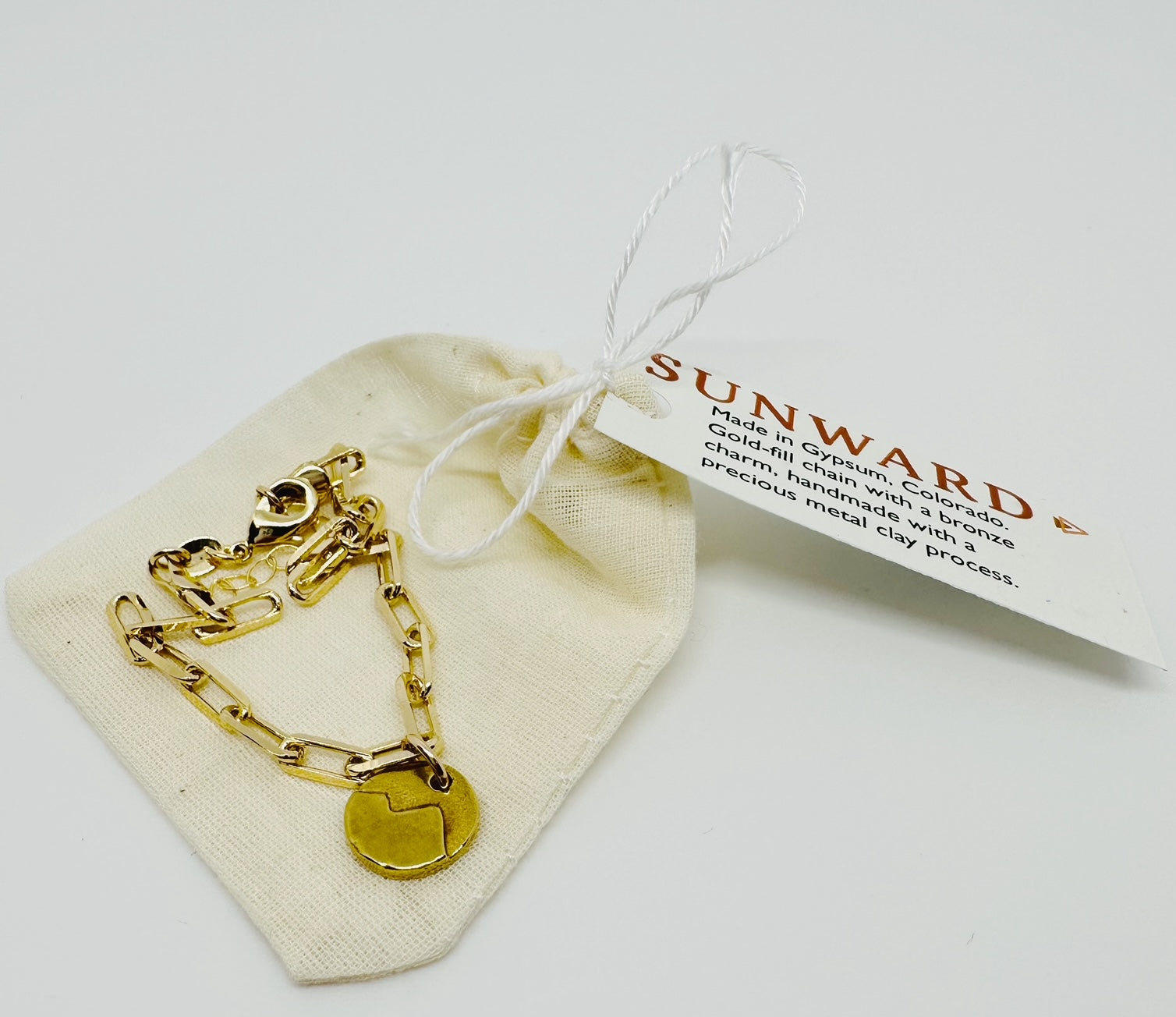 Mountain Link Bracelet on fabric bag. Gold-fill chain with a bronze mountain charm, handmade with a precious metal clay process. 