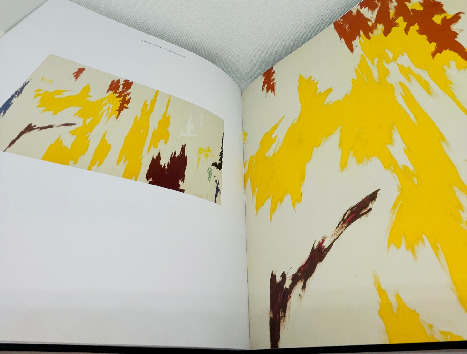Open book with a full abstract painting on the left page and a closeup of the painting on the right page featuring abstract yellow, red, and dark red shapes