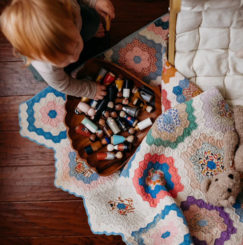 Top view photo of a child playing with an assortment of wooden dolls